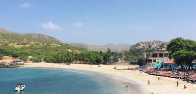 Bunte Fischerboote und Personen am weißen Sandstrand