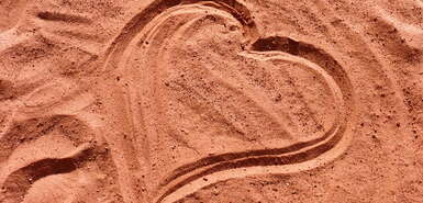 Mit dem Finger gemaltes Herz im Sand