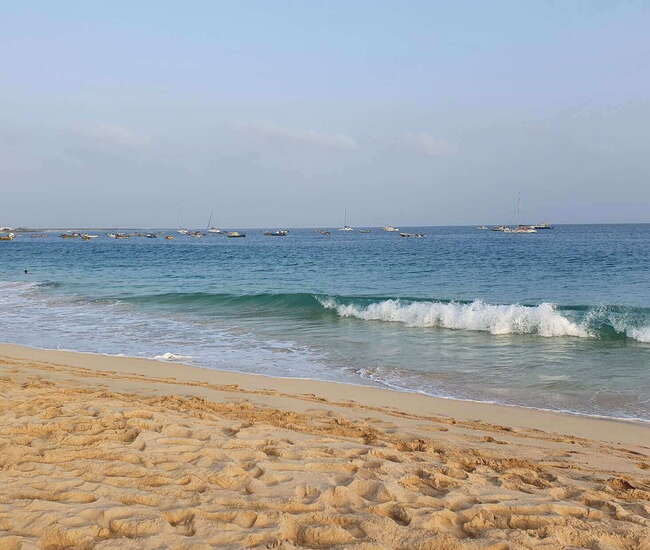 Sand und blaues Meer mit Wellen auf Sal