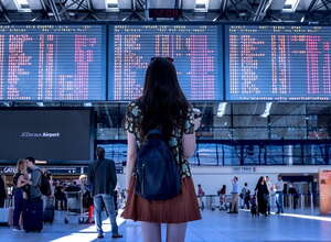 Frau vor Abflugtafeln am Flughafen